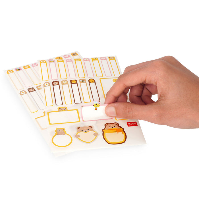 Hand holding a sheet of decorative labels with animal designs on a white background