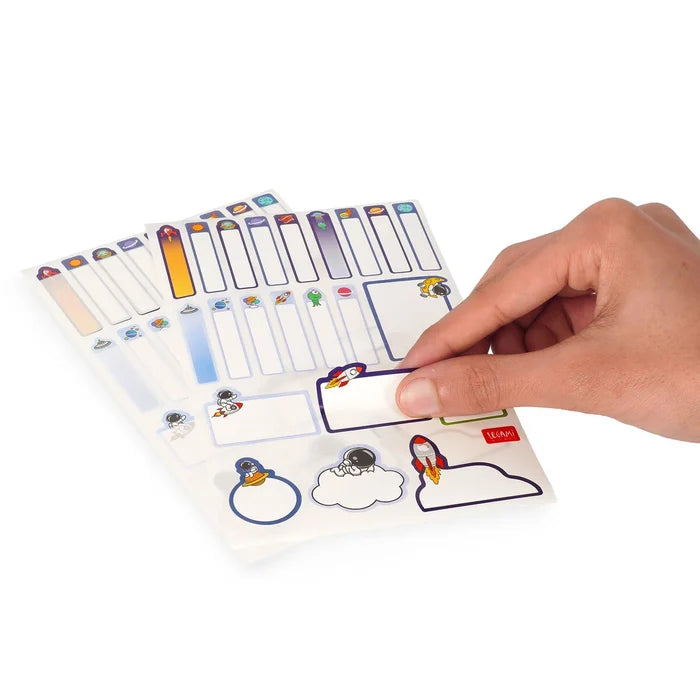 Hand holding a colorful set of name tags with various space designs on a white background