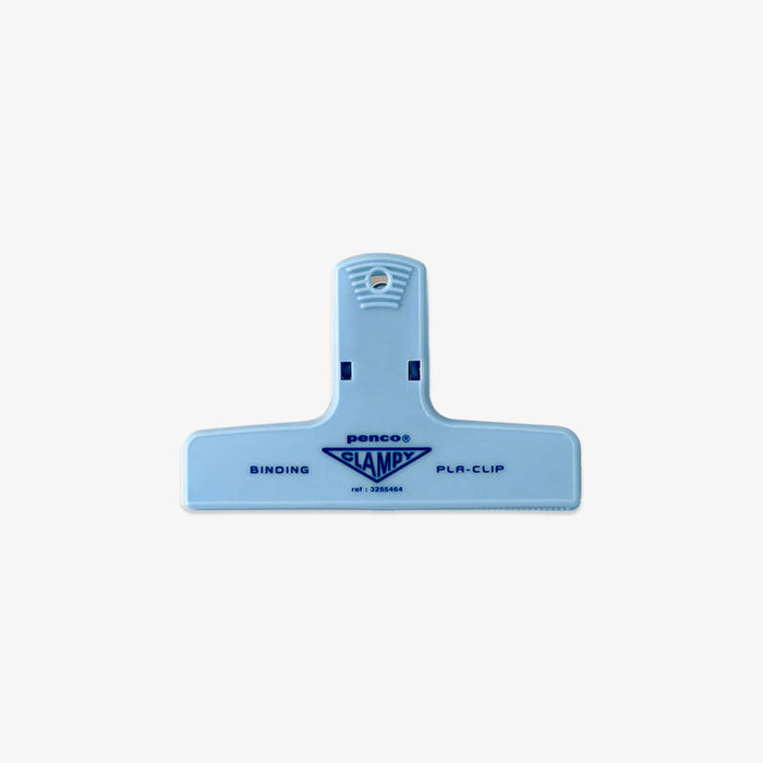 A light blue plastic binding clip with the brand name 'Pencas' and model 'SLAMPS' printed in dark blue on the front, set against a plain light gray background.