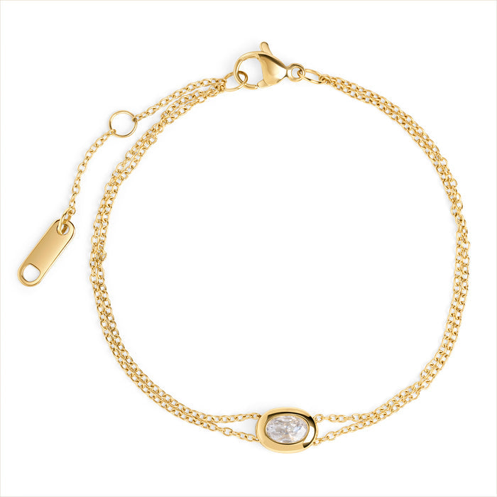 A double gold chain bracelet with an oval clear stone centerpiece, shown on a clean white background. Waterproof, stainless steel and allergy free. By Mia Bijoux Canada.

Bracelet à double chaîne dorée orné d'une pierre transparente ovale en son centre, présenté sur fond blanc épuré. Résistant à l'eau, en acier inoxydable et hypoallergénique. Par Mia Bijoux Canada.