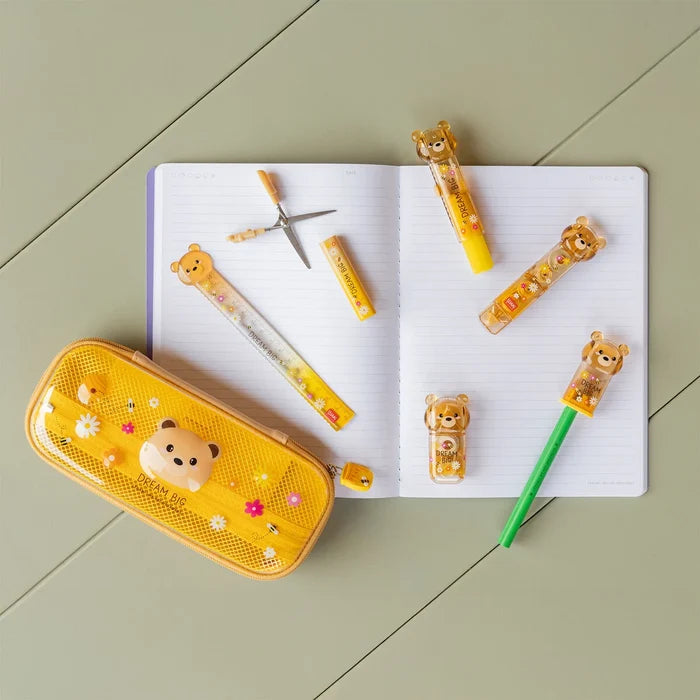Yellow pencil case with teddy bear design on a notebook with teddy bear-themed stationery items on a green tiled floor.