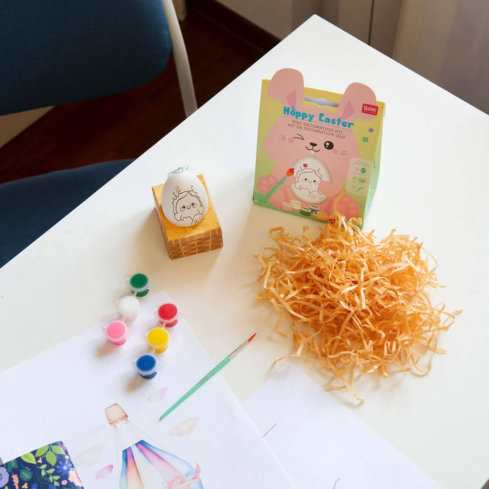 Easter-themed craft supplies including paint, paper, and a box on a table.