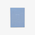 A light blue hardcover notebook with the word 'GRATITUDE' printed on the cover in capital letters.
