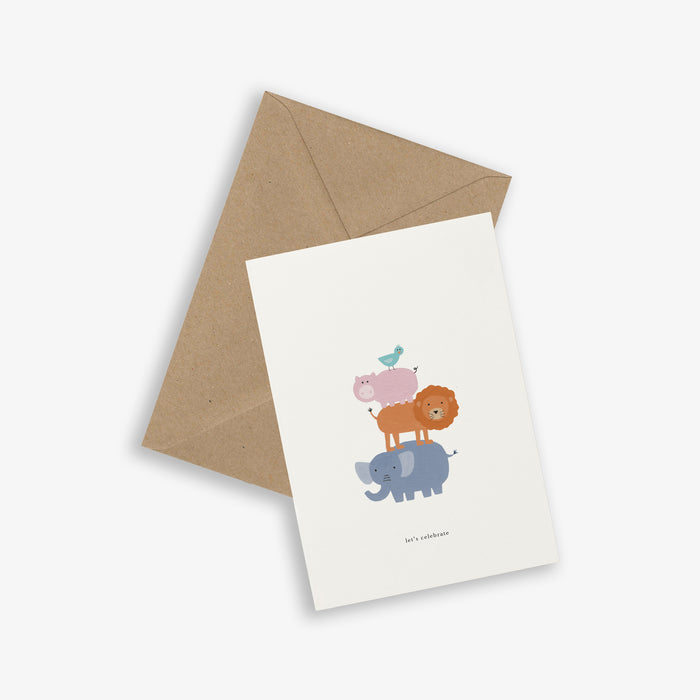 A greeting card with a illustration of an animal tower  (consisting of a bird, a pig, a lion and an elephant) and the text 'let's celebrate' accompanied by a brown kraft envelope.