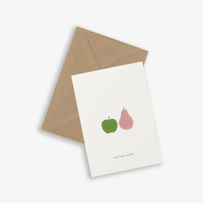 A greeting card with a graphic of an apple and a pear and the text 'every body is perfect' accompanied by a brown kraft envelope, on a white background.