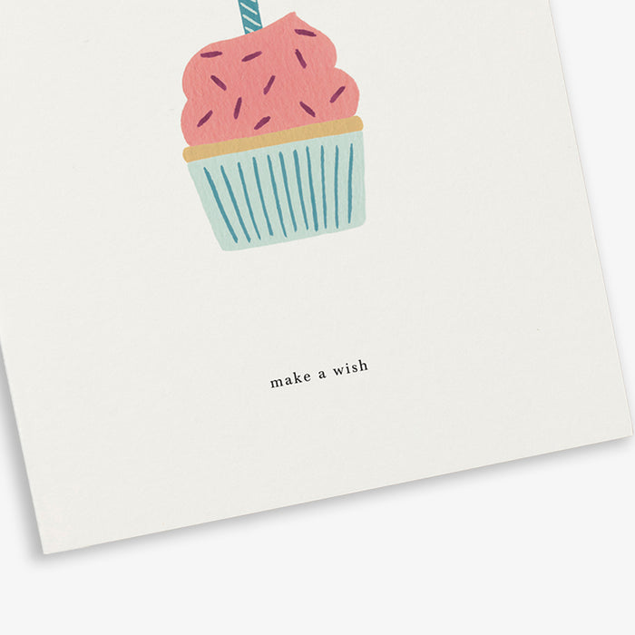 A folded birthday greeting card with an illustration of a birthday cake and with the text 'make a wish'.