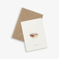 A greeting card with an illustration of a book stack and the phrase 'sorry, i'm booked.' accompanied by a brown kraft envelope.