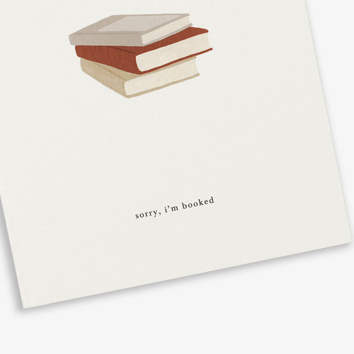 A greeting card with an illustration of a book stack and the phrase 'sorry, i'm booked'.