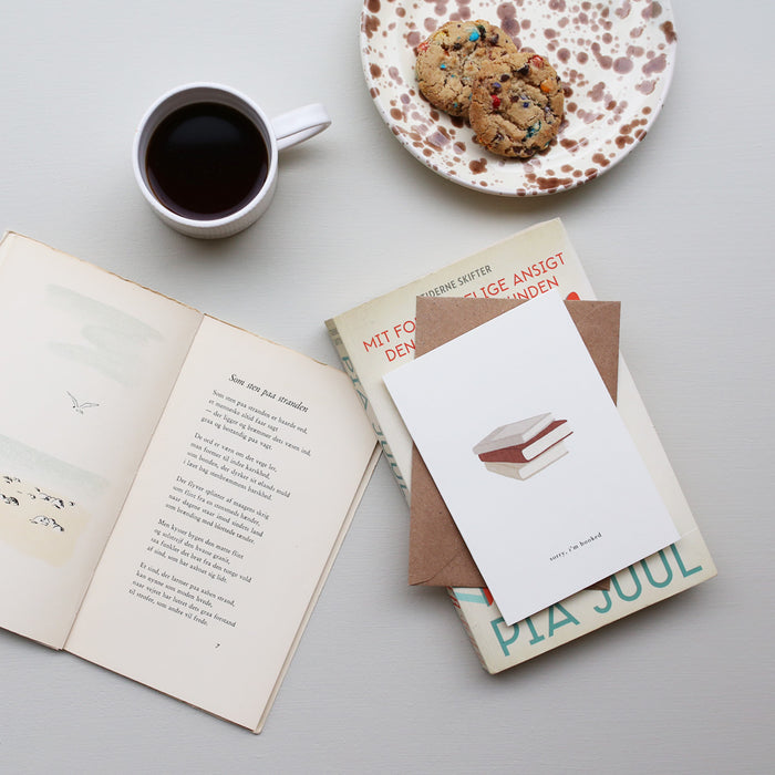 Table setup with the greeting card with a bookstack illustration and the text 'sorry, i'm booked'.