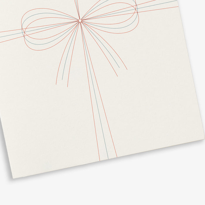 Close up on a simple white A6 greeting card with the text 'SIMPLY PERFECT' and a graphic of a bow.