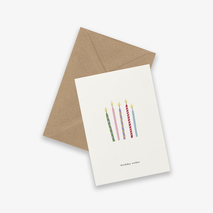 Greeting card with birthday candles and 'birthday wishes' text and brown envelope on white background