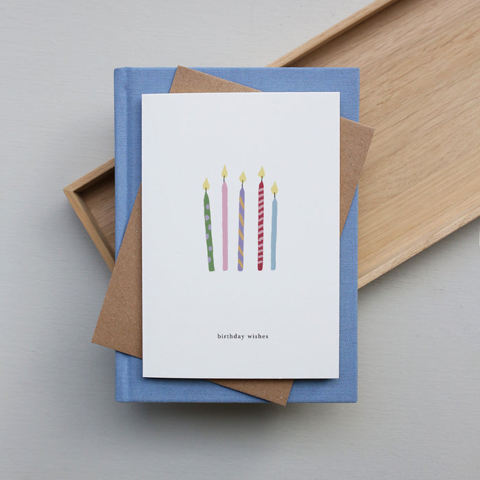 Greeting card with birthday candles design and 'birthday wishes' text on a blue box with brown paper