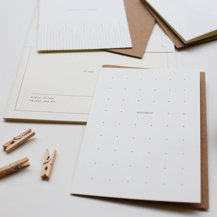 A simple, illustrated greeting card with the text 'HOORAY' on it with dots pattern, accompanied by a brown kraft envelope.