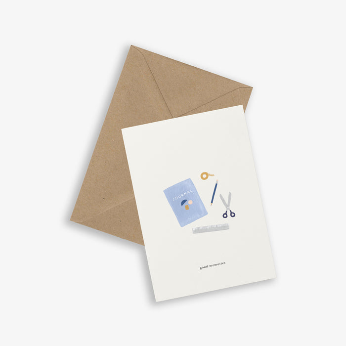A simple, illustrated greeting card A simple, illustrated greeting card with a journal, pencil, scissor and a come with the phrase 'good memories' written on it, accompanied by a brown kraft envelope. The card is displayed against a white background.