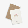 A greeting card with a rainbow illustration and the text 'lucky in love' accompanied by a brown kraft envelope, displayed on a white background.