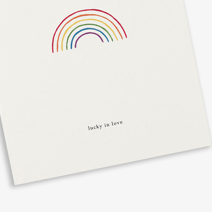 A greeting card with a rainbow illustration and the text 'lucky in love'.
