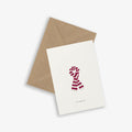 A simple illustrated greeting card with a scarf design with the text 'all wrapped up' accompanied by a brown kraft envelope, displayed on a white background.
