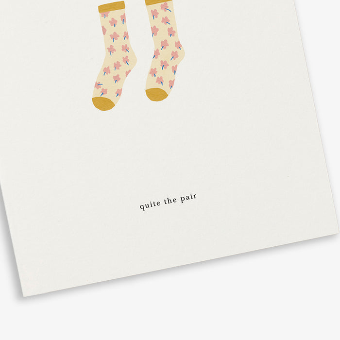 A greeting card with an illustration of socks and the text 'quite the pair'.