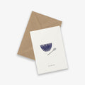 A greeting card with a soup bowl illustration and a spoon and the text 'get well soon', accompanied by a brown kraft envelope, on a white background.