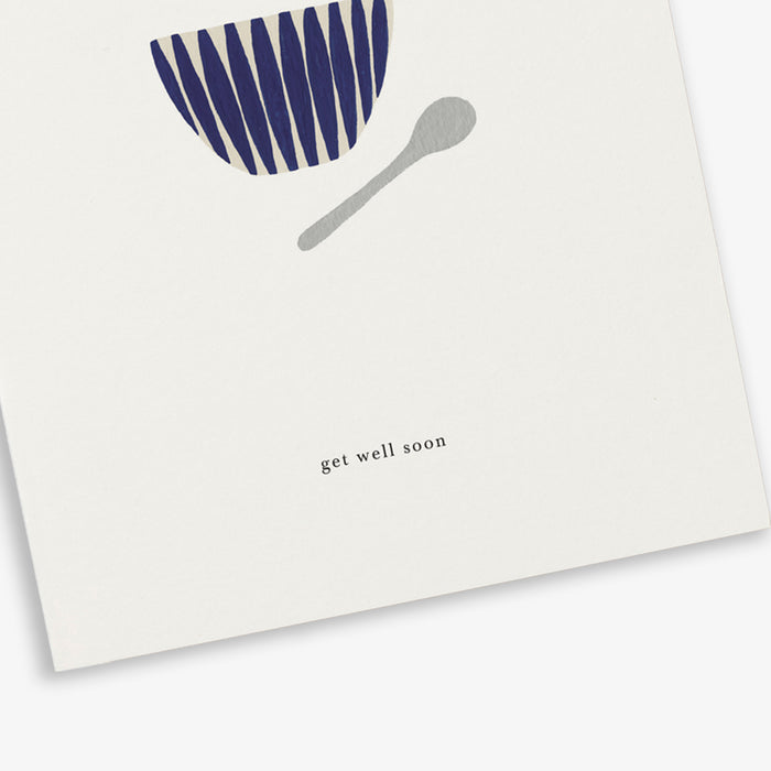 A greeting card with a soup bowl illustration and a spoon and the text 'get well soon'.