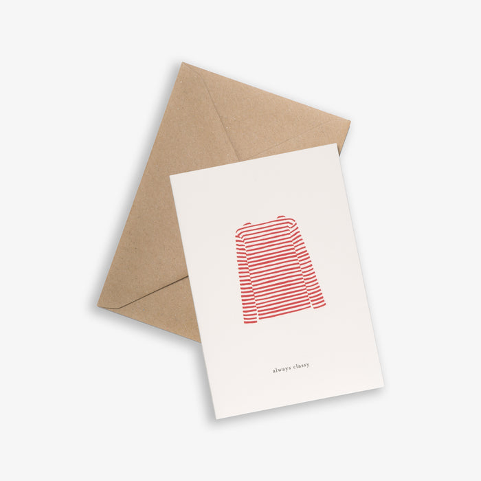 A white greeting card with a red striped sweater illustration and the text 'ALWAYS CLASSY' below it, accompanied by a brown kraft envelope, presented on a light background.