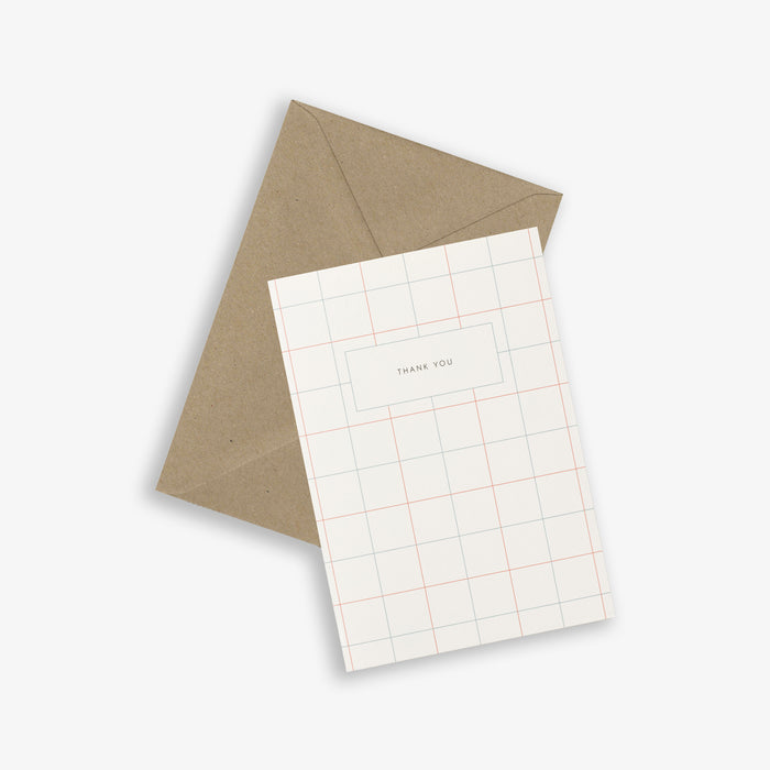 A simple, folded A6 greeting card with a grid pattern and the text 'THANK YOU' accompanied by a brown kraft envelope.