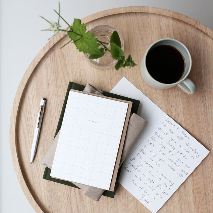 Table set up with greeting cards and the text 'THNAK YOU' on a gridded card with crafted envelope.