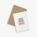 A Christmas-themed greeting card with a sweater pattern and the text 'warm wishes' on it, accompanied by a brown kraft envelope.