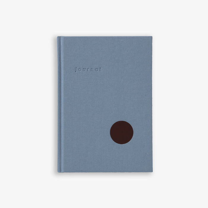 A light blue hardcover notebook with a simple design and a dark brown circular detail on the cover.