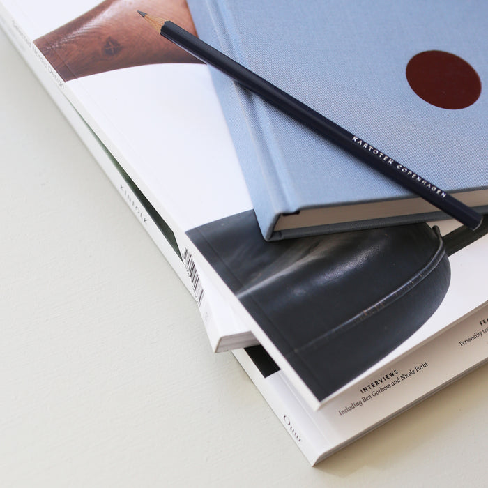 Table setup with a light blue hardcover notebook and a pencil.