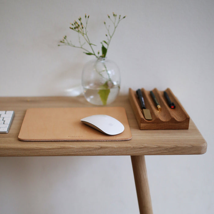 Mousepad in leather displayed with mouse on a desk.