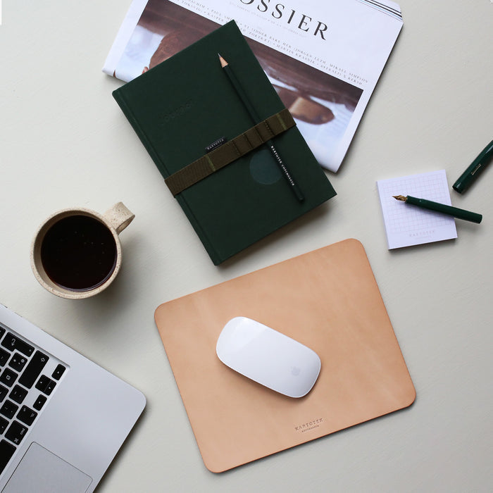 Mousepad in leather displayed with mouse on a desk.