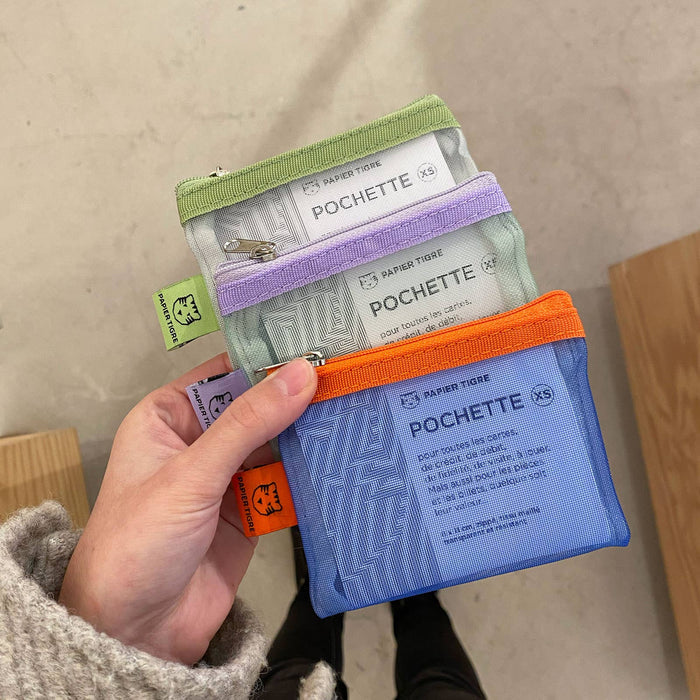 Hand holding a set of small mesh pouches with visible branding on a neutral background