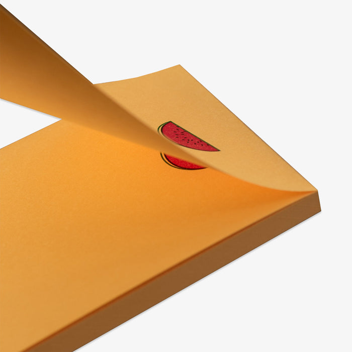 Close-up of a yellow notepad with a red watermelon sticker on a white background