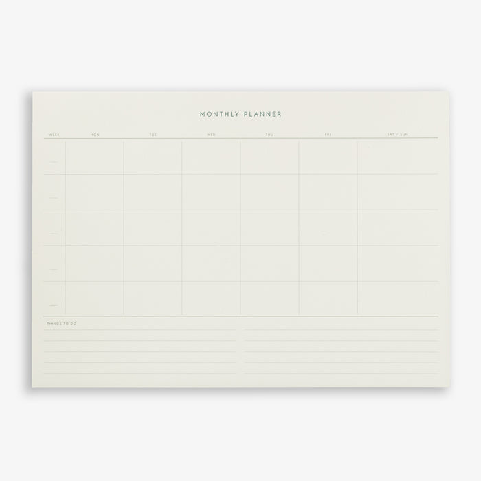 A monthly planner notepad with a grid layout, titled 'MONTHLY PLANNER', on a plain background.