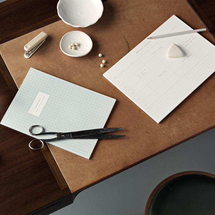 Table set up with a Monthly Planner notepad and other stationary products.
