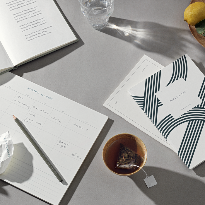 Table set up with a Monthly Planner notepad and other stationary products.