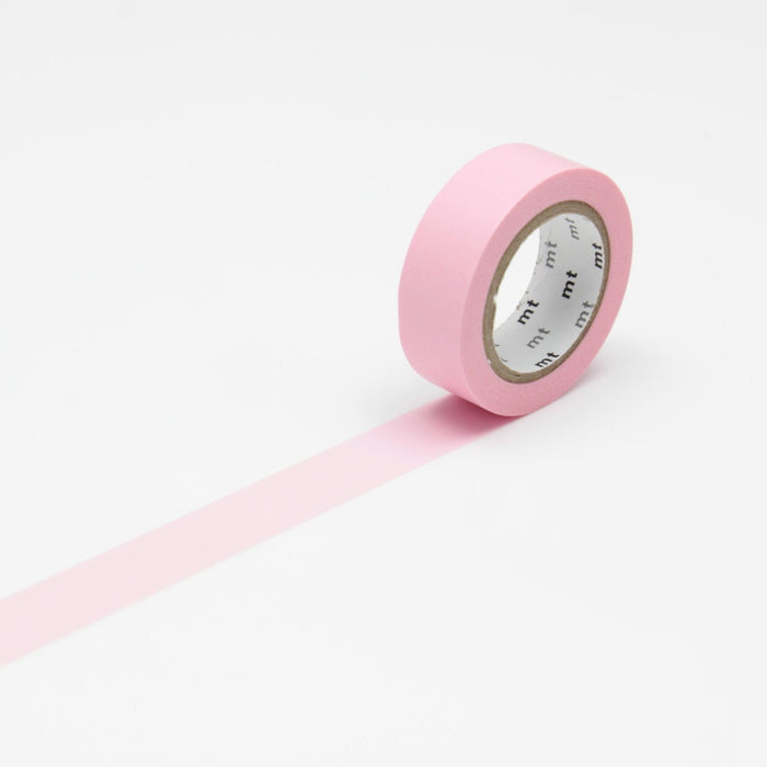 A roll of rose pink masking tape unrolled on a white background