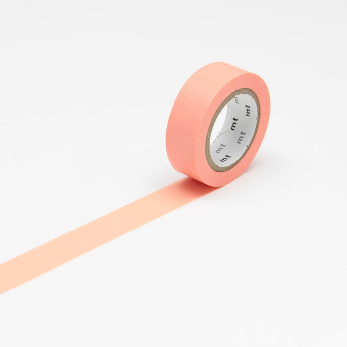 A roll of salmon pink masking tape unrolled on a white background