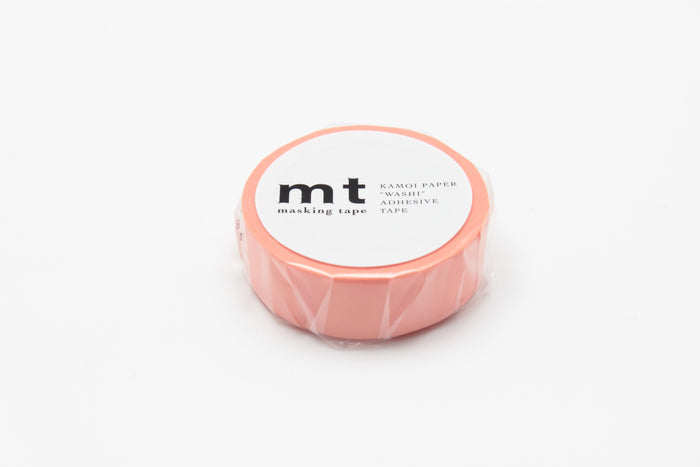 A roll of salmon pink masking tape on a white background