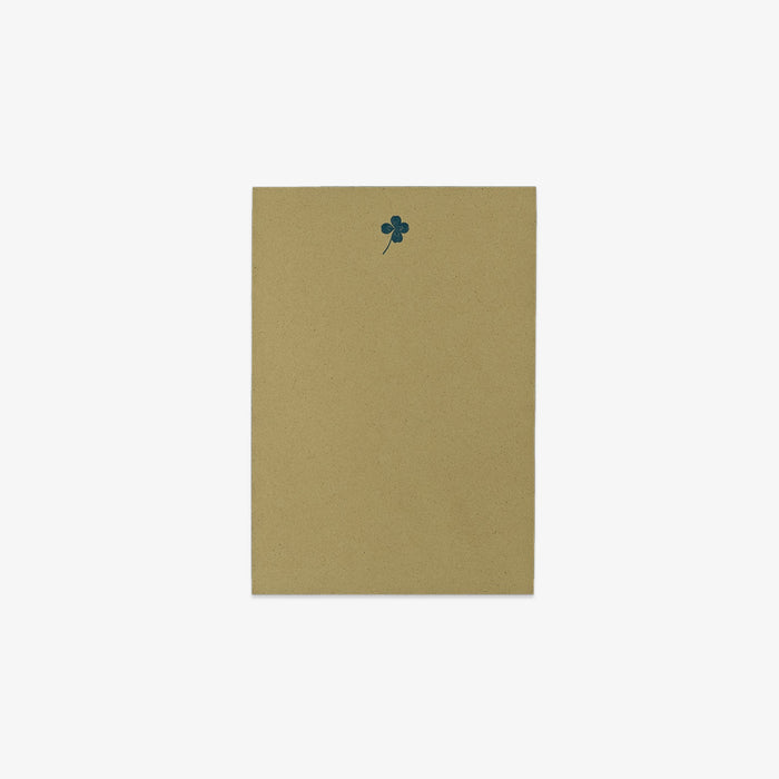 Green notepad with a dark green clover design on a white background