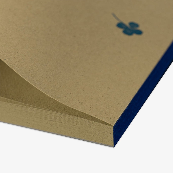 Close-up of a green notepad with a blue stripe and a clover design on a white background