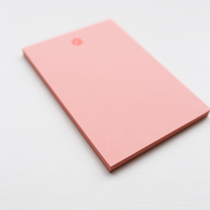 Pink notepad with paw print on a light gray background