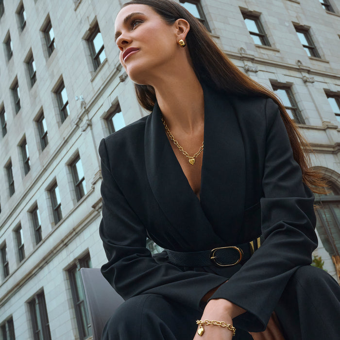 Gold stainless steel chunky chain necklace with heart pendant and matching bracelet, worn with gold statement stud earrings, bold elegant jewelry styling, hypoallergenic non-tarnish durable everyday jewelry.