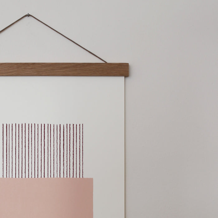 A light pink and white geometric line print framed in an oak frame, with a magnetic closure.
