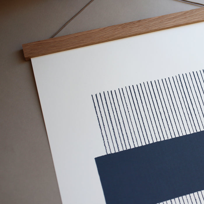 A navy and white geometric line print framed in an oak frame, with a magnetic closure.