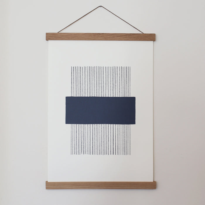 A navy and white geometric line print framed in an oak frame, with a magnetic closure.
