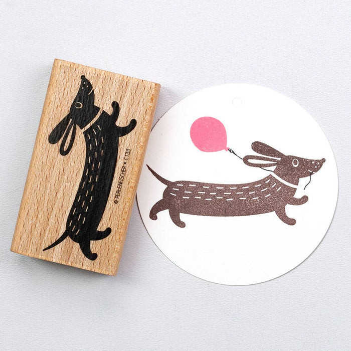 Wooden stamp with a dachshund design and a matching printed design on paper.