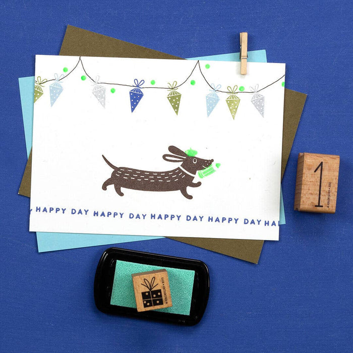 Greeting card with a dachshund illustration and decorative elements on a blue background