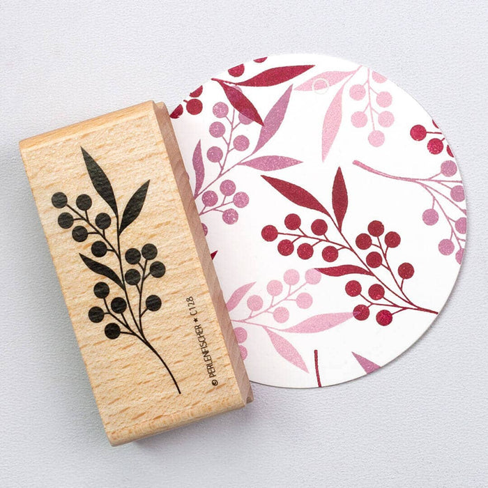 Rubber stamp with wildberry design next to a circular product with similar pattern on a light gray background